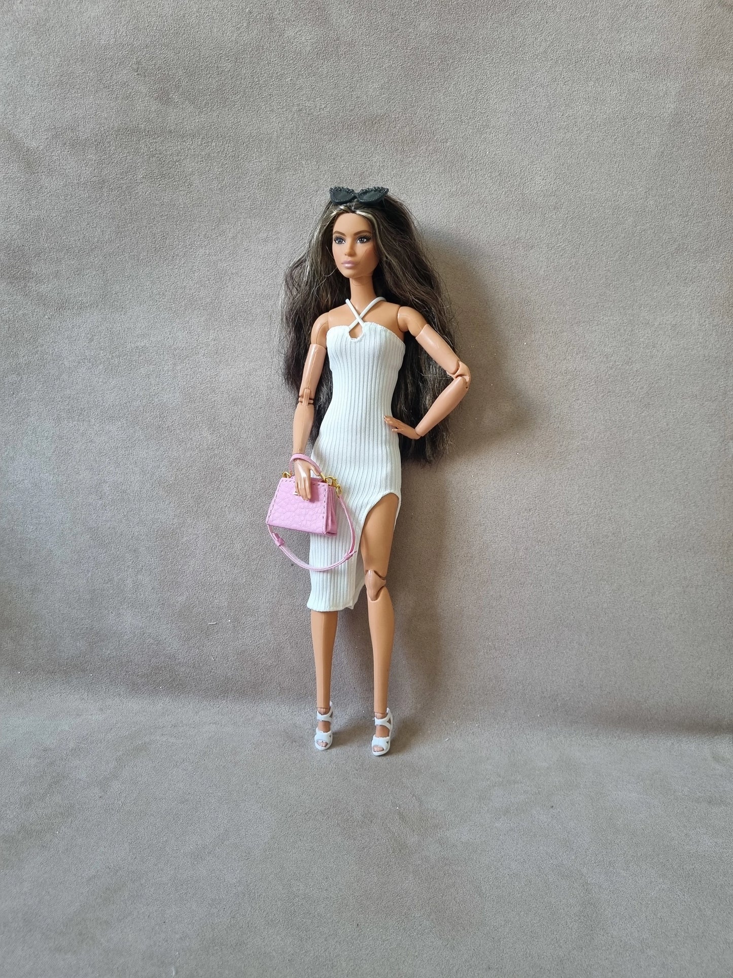 Barbie doll wearing white ribbed midi dress without sleeves, holding pink purse, sunglasses on head, white heels.