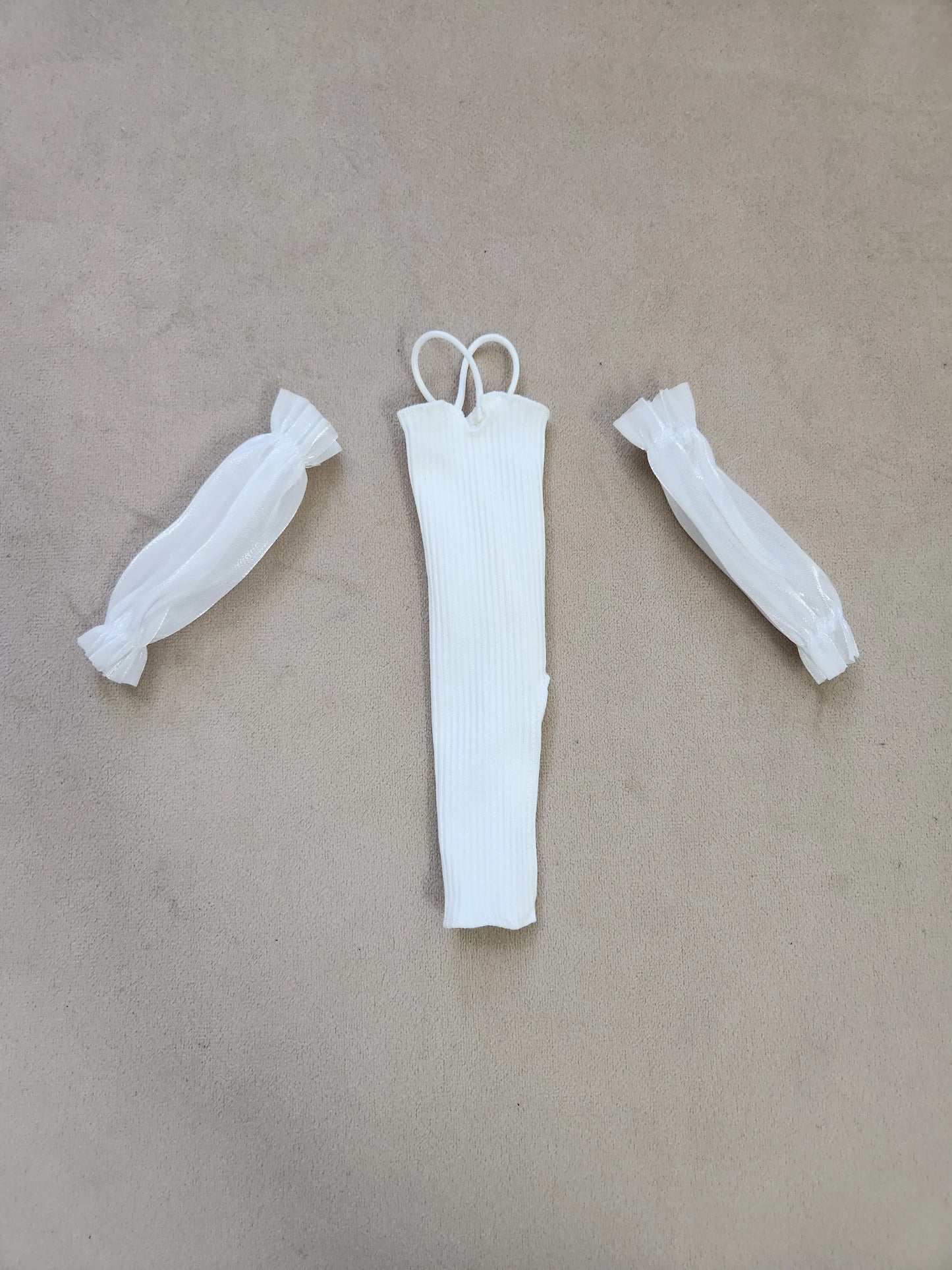 Barbie outfit components flat lay: white ribbed halter midi dress and separate sheer white puff sleeves on beige background.
