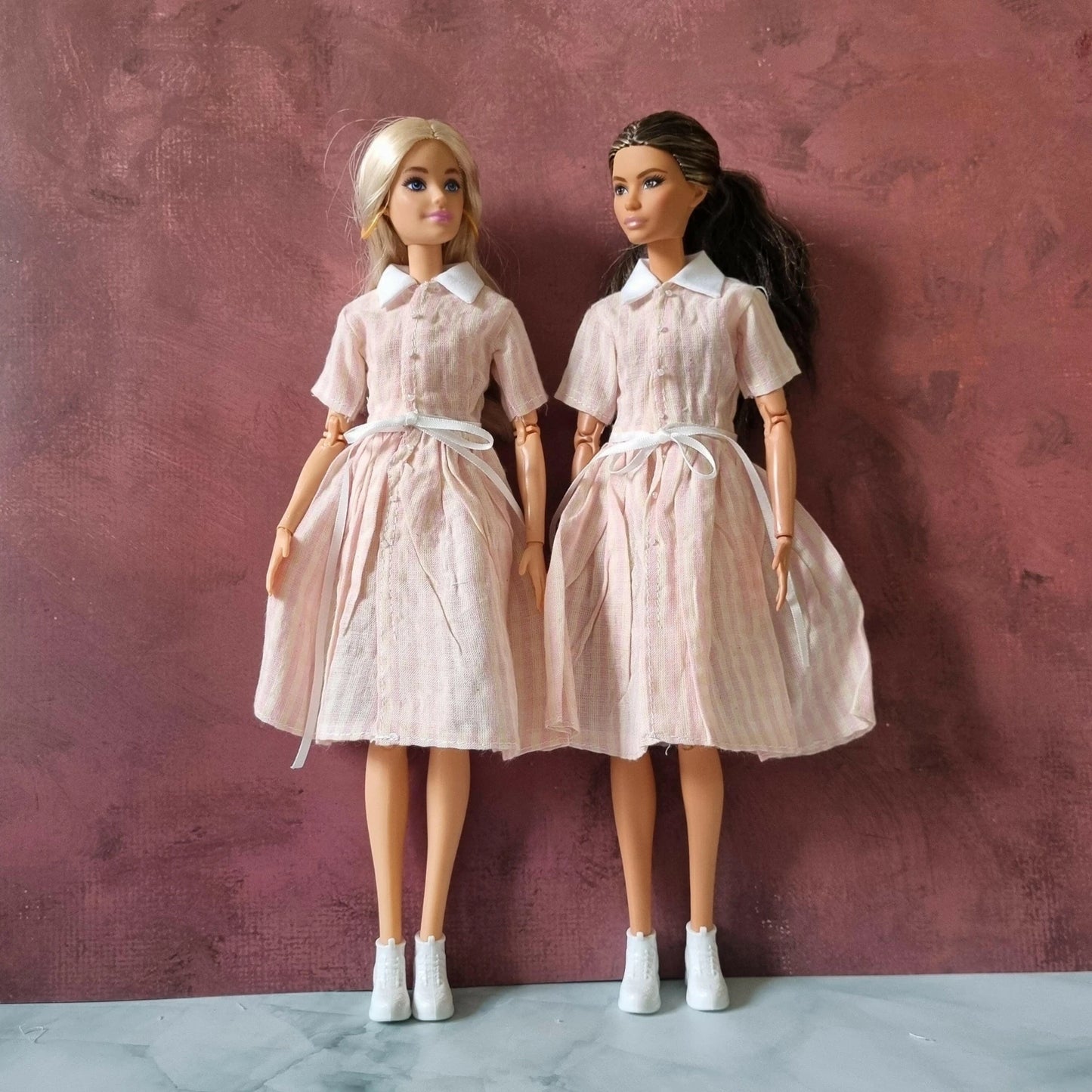 Two Barbie dolls wearing pink striped retro shirt dresses with collars and ties