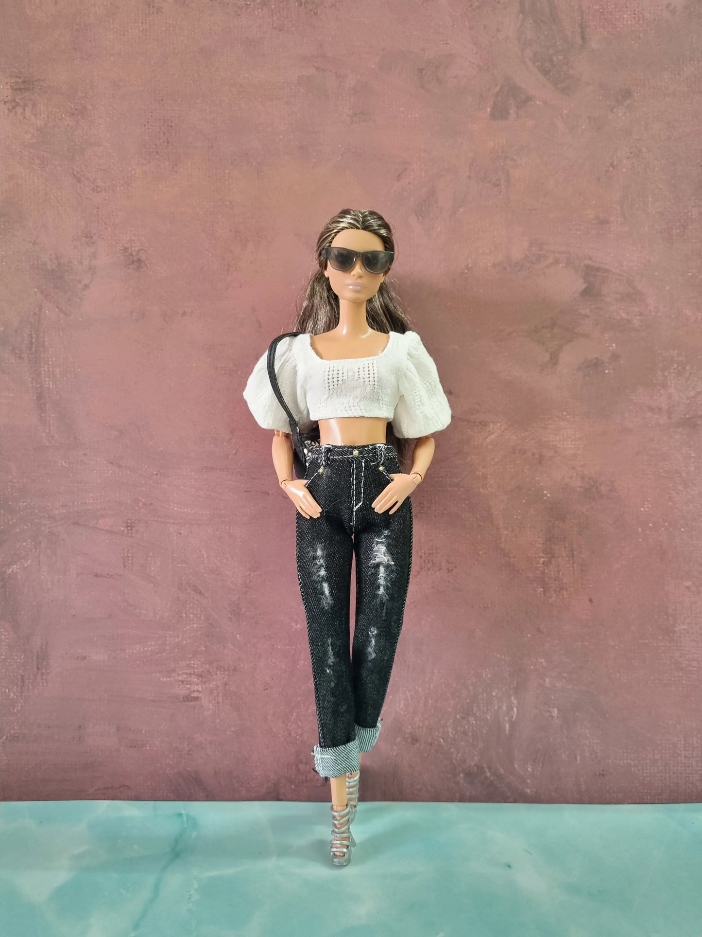 Barbie doll modeling a white textured puff sleeve crop top and black distressed jeans with rolled cuffs.