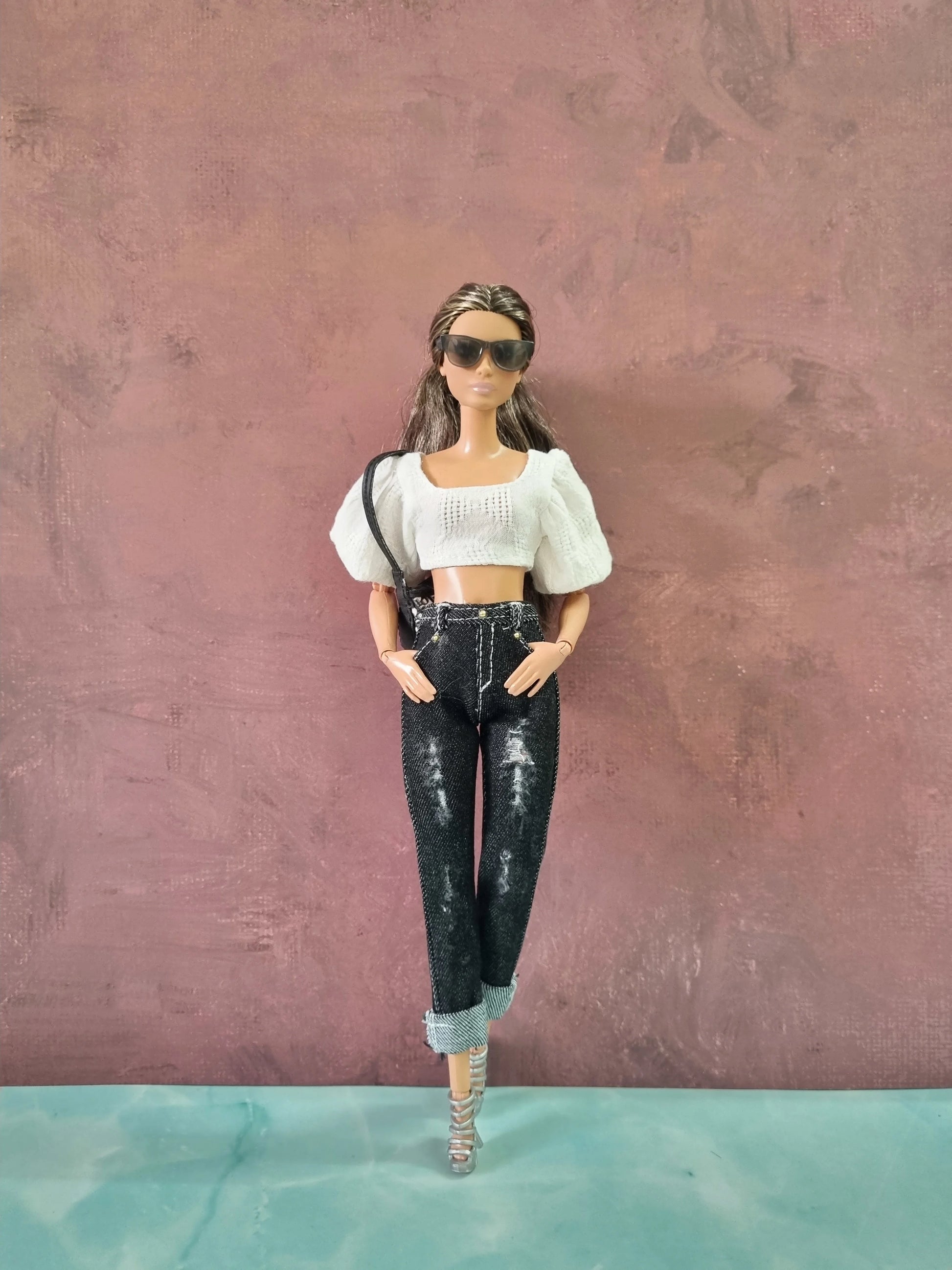 Barbie doll modeling a white textured puff sleeve crop top and black distressed jeans with rolled cuffs.