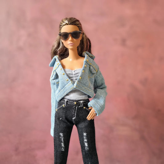Barbie doll modeling a light blue denim jacket with gold studs, black distressed jeans, and sunglasses.