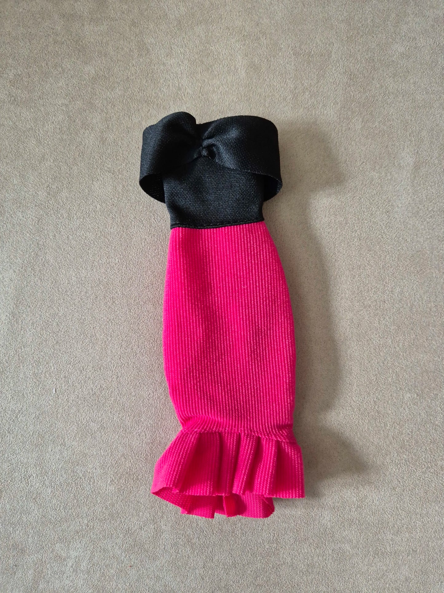 Barbie doll outfit flat lay: black off-shoulder top and hot pink ribbed mermaid skirt with ruffle.