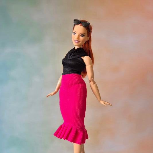 Barbie doll models elegant black top and hot pink mermaid ruffle skirt, side view.