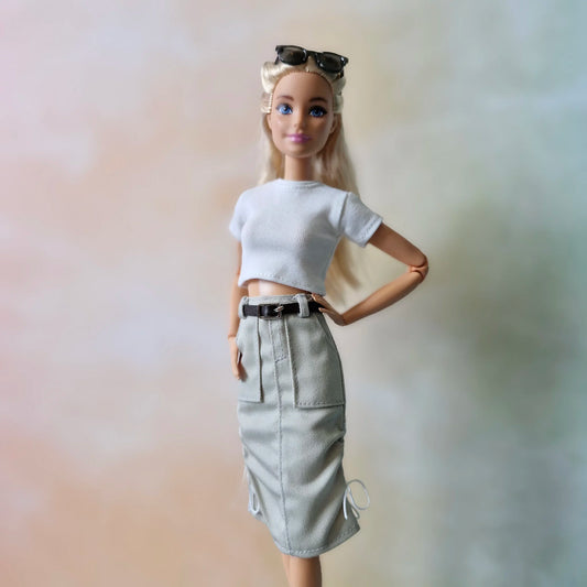 Barbie doll wearing a white crop top and khaki skirt with a black belt.