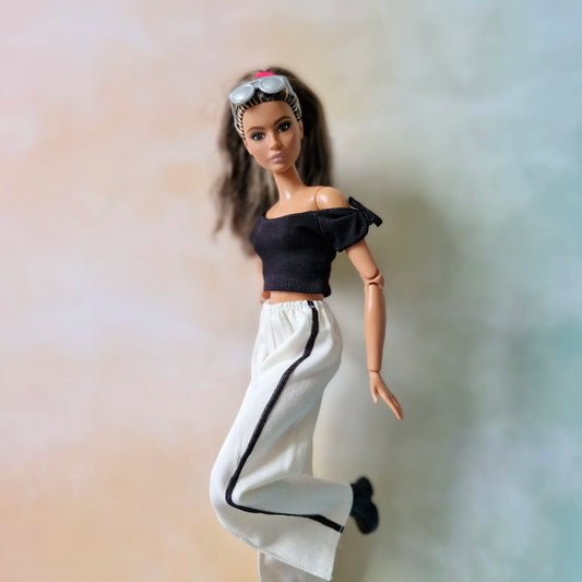 Side view of Barbie in black off-shoulder crop top and white striped pants casual outfit.