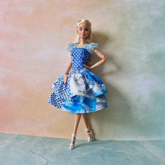 Blue mixed print Barbie doll dress featuring geometric and floral patterns on a layered skirt.