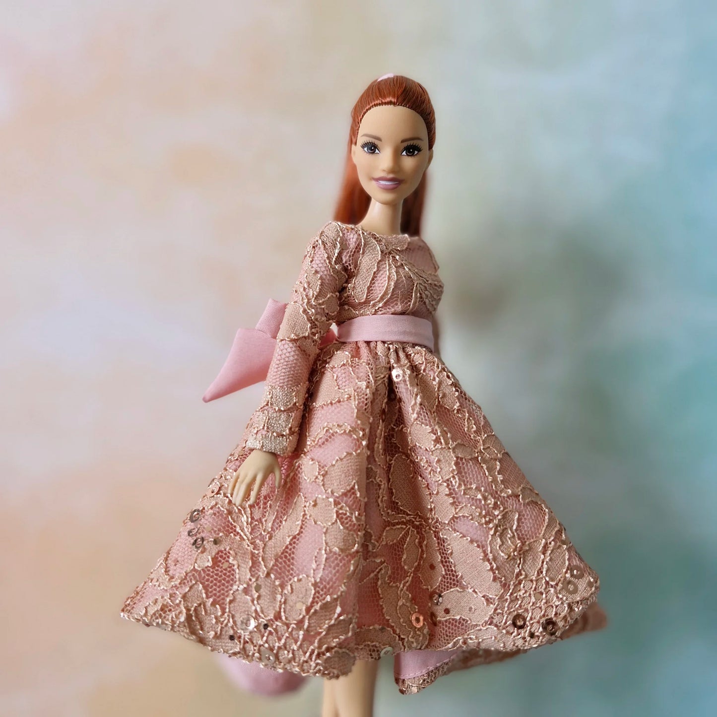 Barbie Curvy doll showcasing dusty pink sequin lace gown with elegant back bow detail and high-low hemline.