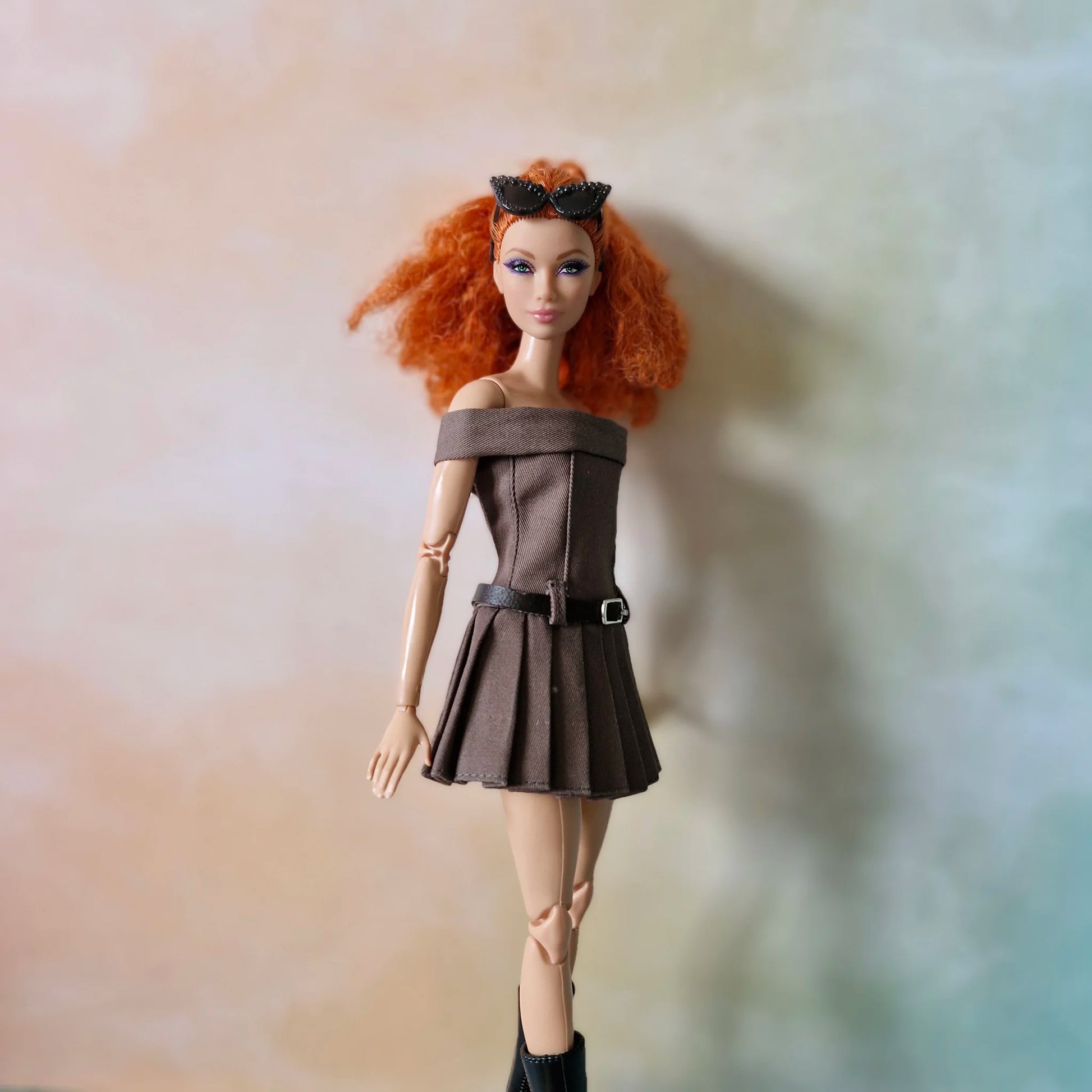 Redhead Barbie doll wearing brown off-shoulder pleated dress, sunglasses, and black boots
