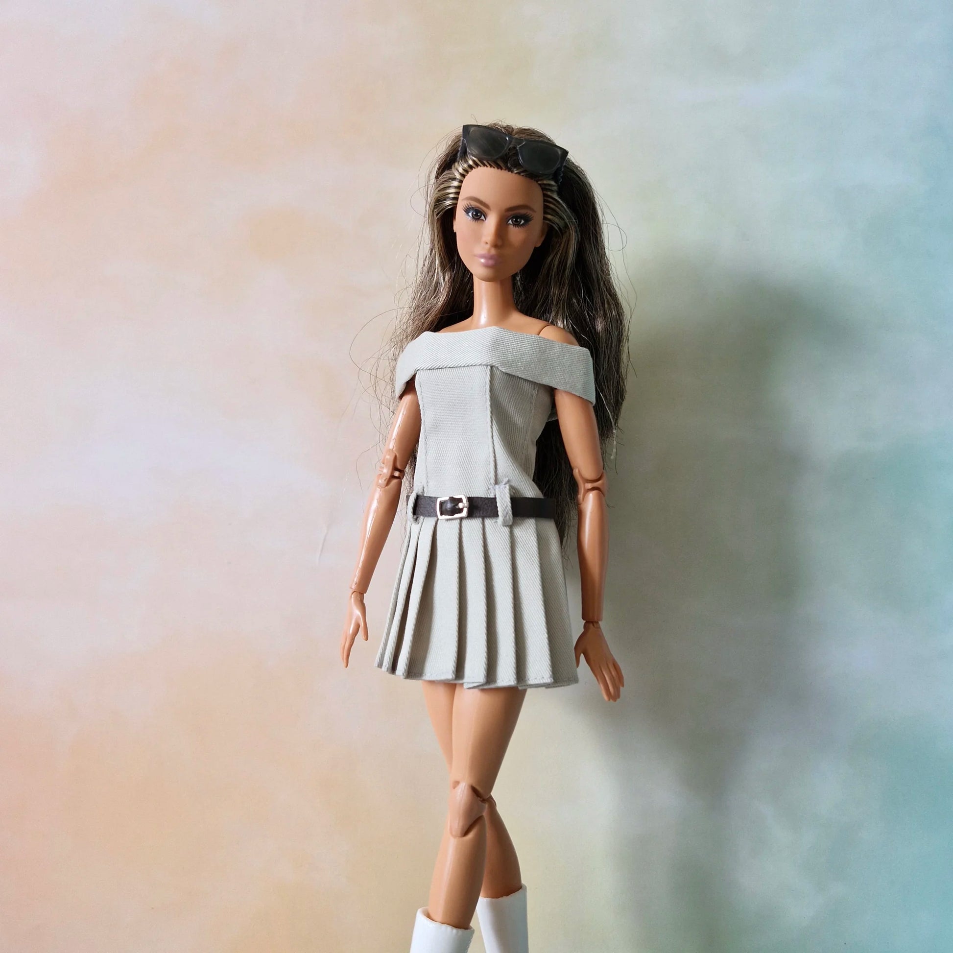 BarbieBarbie doll wearing grey off-shoulder pleated dress with belt, sunglasses on head, and white boots doll wearing grey off-shoulder pleated dress with belt, sunglasses on head, and white boots