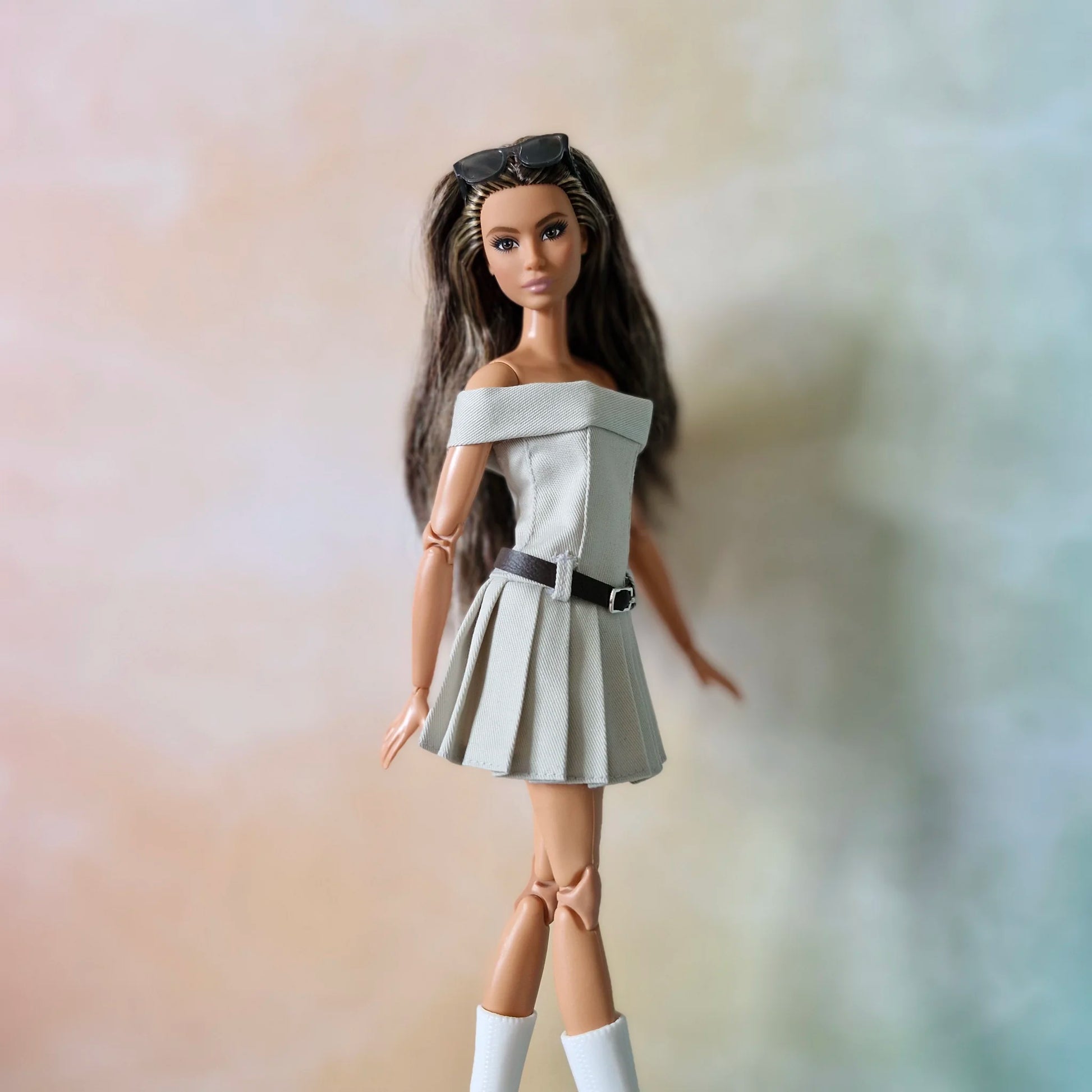 Barbie doll models grey off-shoulder pleated dress and white boots in walking pose