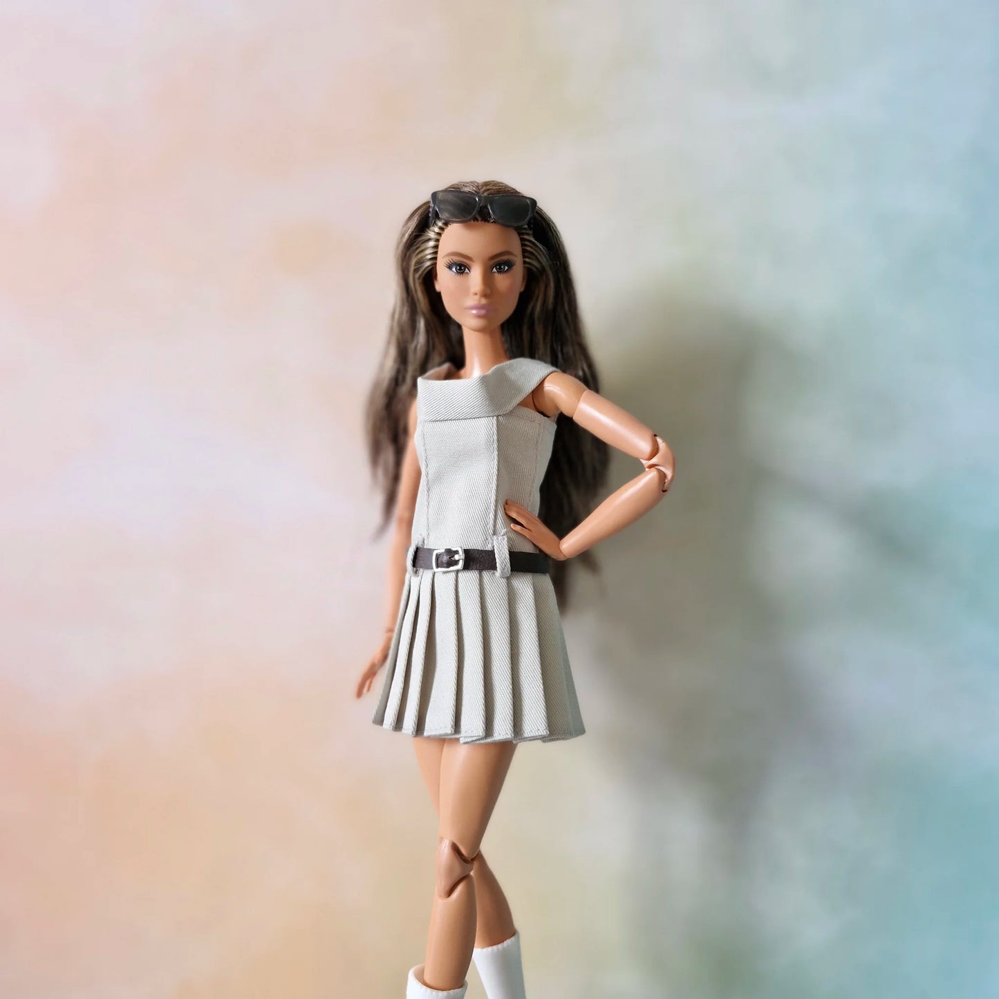 Barbie doll in grey off-shoulder pleated dress poses with hand on hip