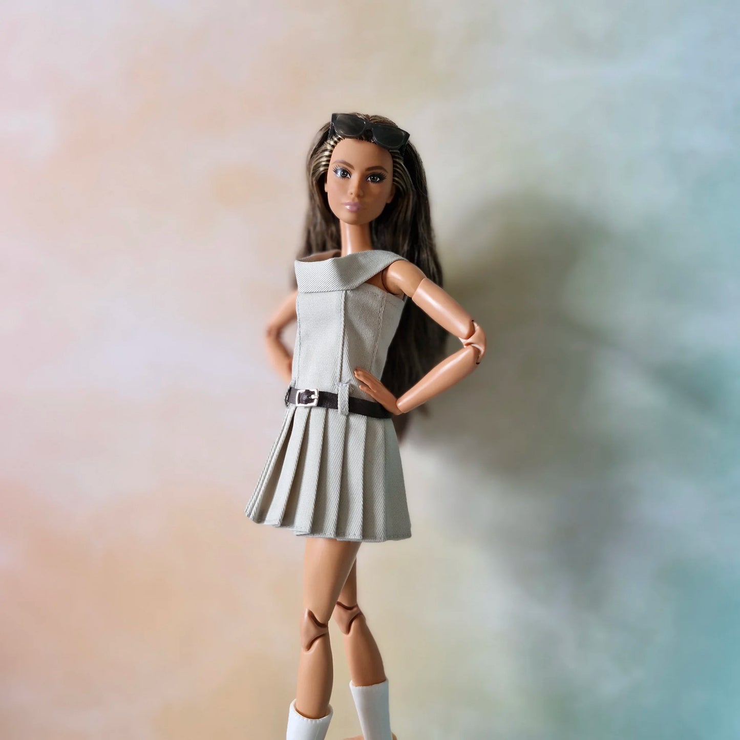 Barbie doll stands confidently in grey off-shoulder pleated dress with hands on hips