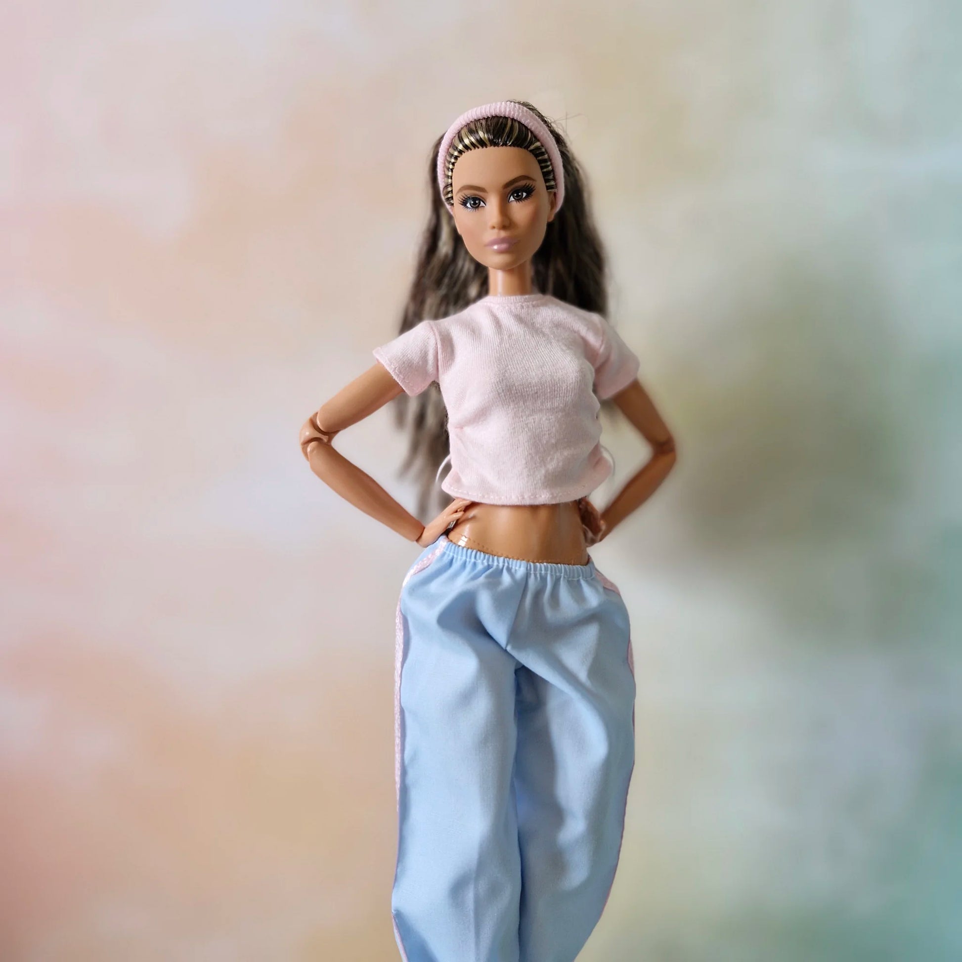 Close-up view of Barbie doll modeling pink textured top with drawstrings and blue pants with pink stripe detail.