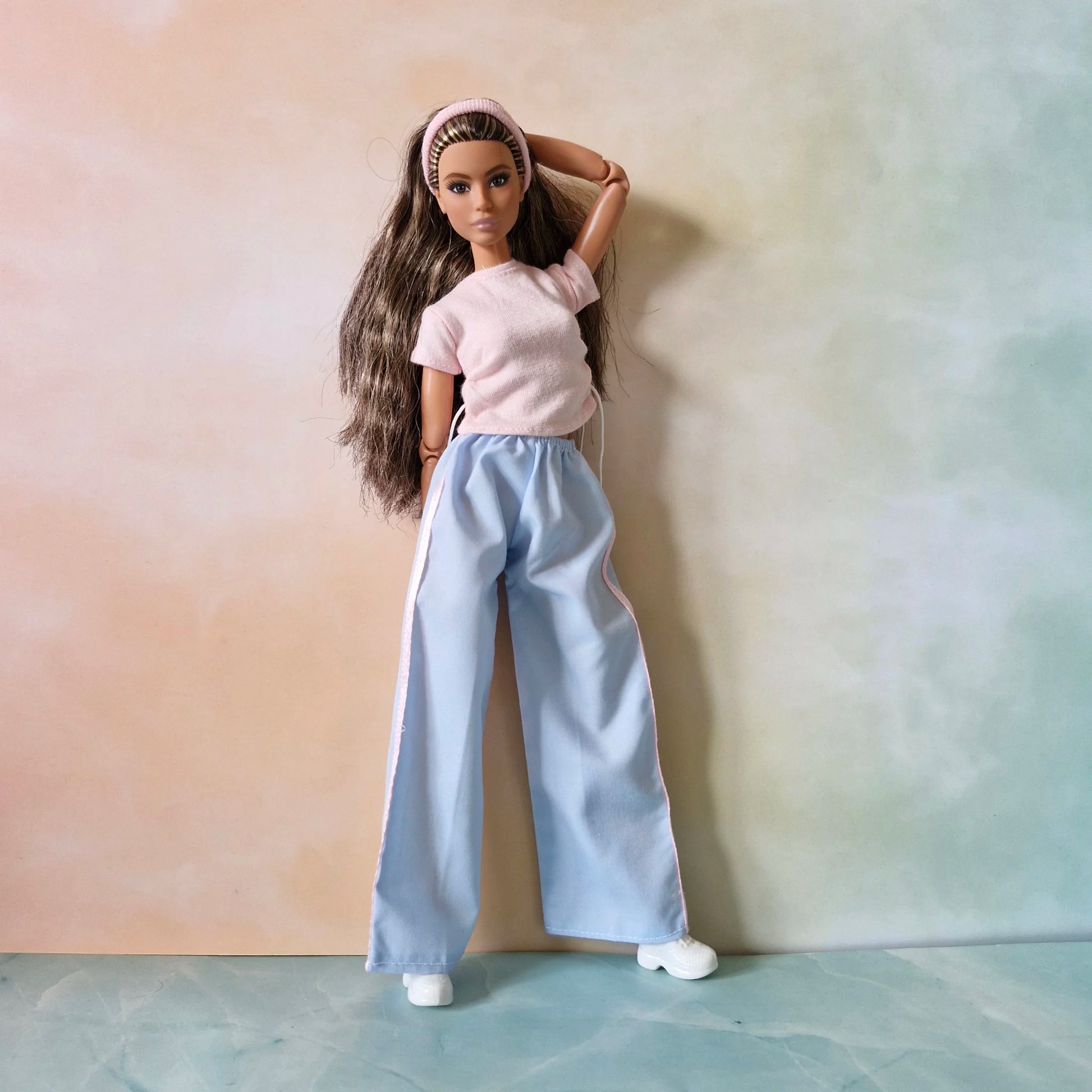 Fashion doll in casual sporty set: pink textured t-shirt with drawstrings and light blue wide-leg pants with pink side stripe.