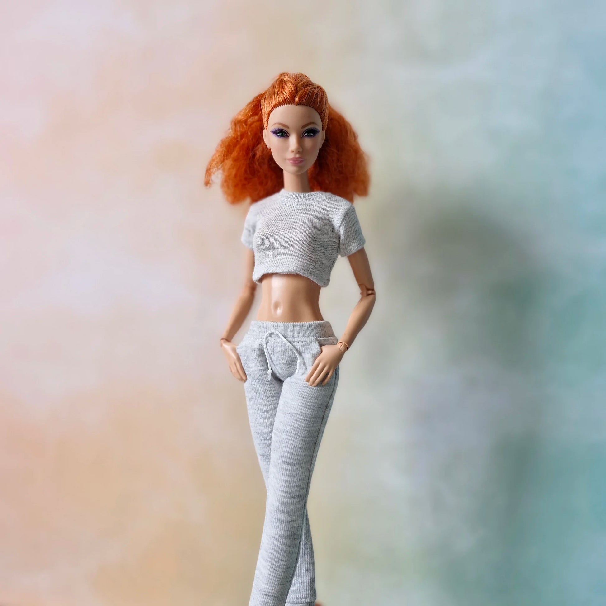 Redhead Barbie doll modeling grey knit loungewear set: classic crop top and slim-fit joggers with drawstring waist.