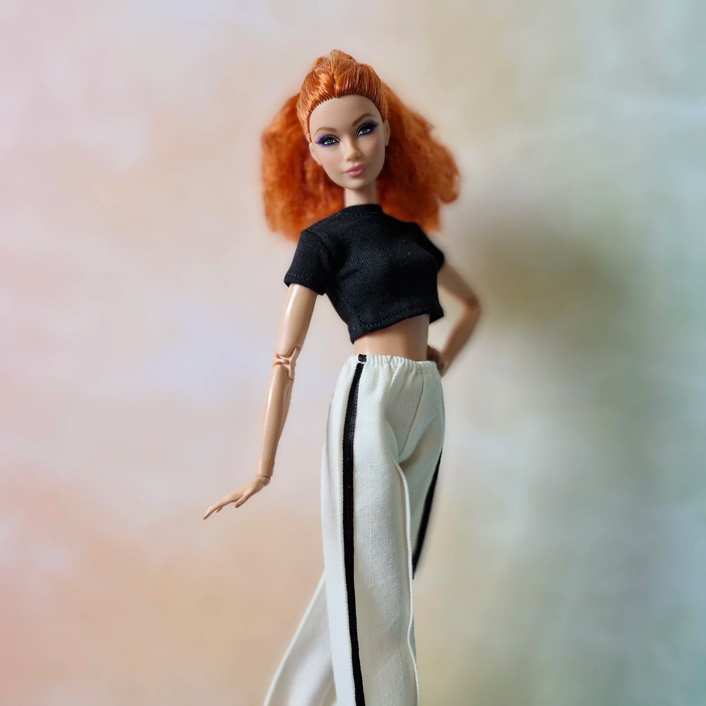 Close-up of red-haired Barbie doll fashion: black crop top and white striped pants.