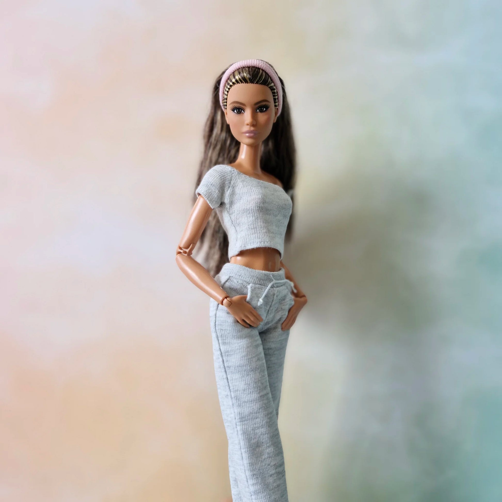 Brunette Barbie doll wearing grey knit classic crop top and slim-fit joggers with drawstring, angled pose.