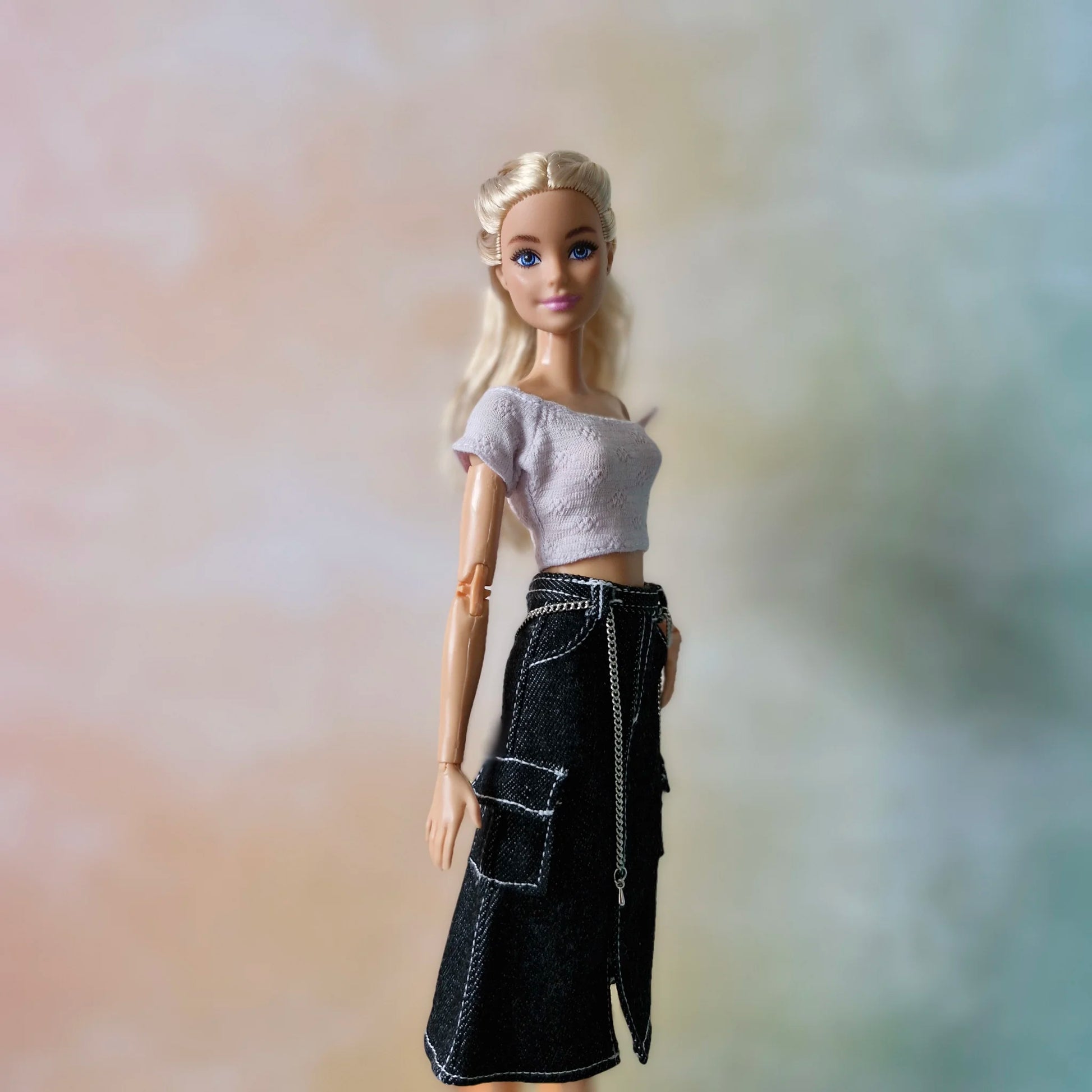 Close-up of Barbie fashion doll wearing lavender off-shoulder top and black cargo midi skirt with white stitching.