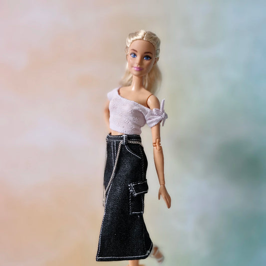 Blonde Barbie doll wearing pale lavender off-shoulder top and black denim cargo midi skirt with chain detail.