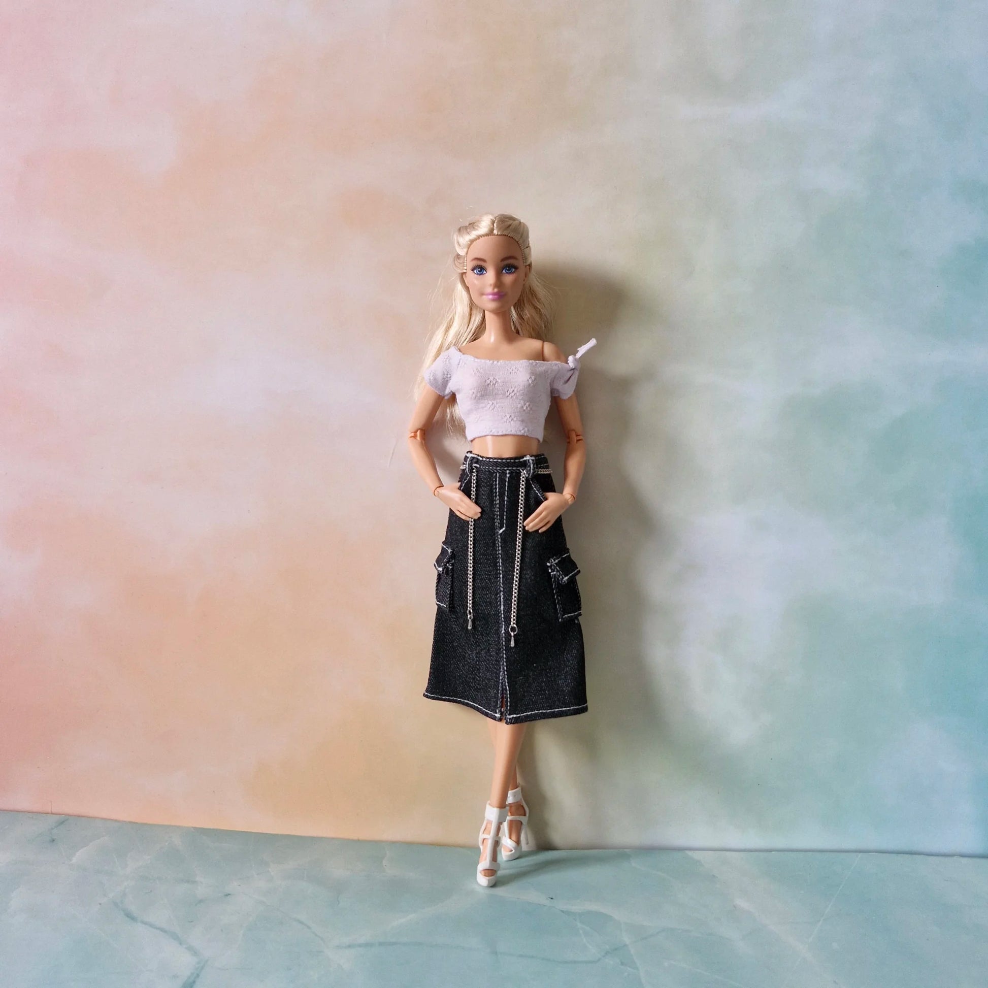 Barbie doll modeling modern outfit set: lavender textured top and dark wash denim midi skirt with cargo pocket and chain.