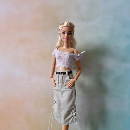 Barbie doll poses in lavender crop top and grey belted midi skirt with front pockets and drawstrings.