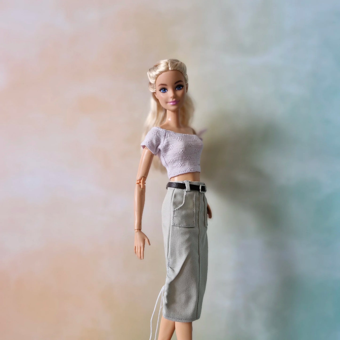 Barbie doll wearing pale lavender off-shoulder top and light grey utility midi skirt with belt and drawstring details.
