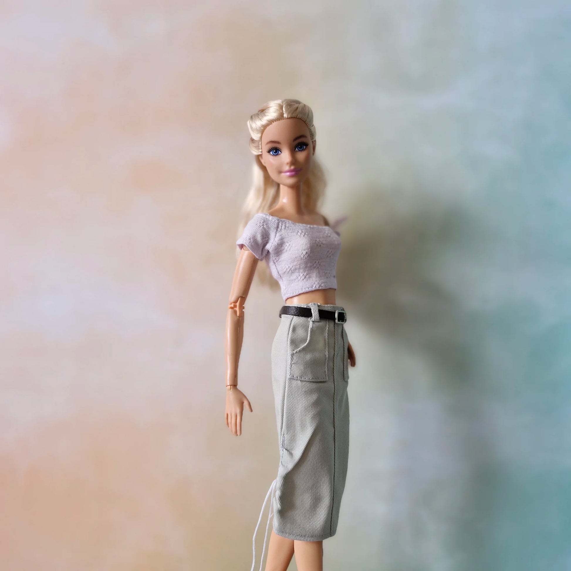 Barbie doll wearing pale lavender off-shoulder top and light grey utility midi skirt with belt and drawstring details.