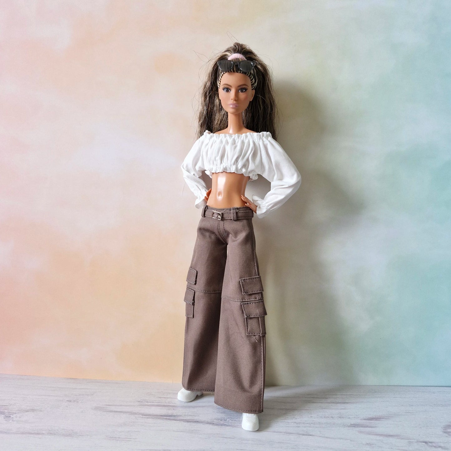 Front view of Barbie doll in white off-shoulder top and brown wide-leg cargo pants, confident stance.