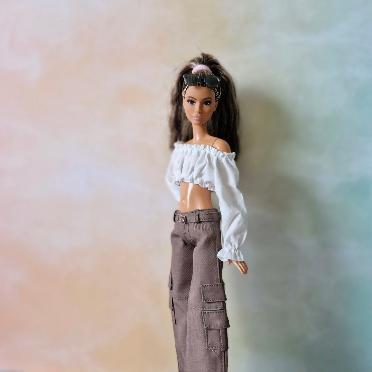 Barbie doll in white off-shoulder crop top and brown wide-leg cargo pants, sunglasses on head.