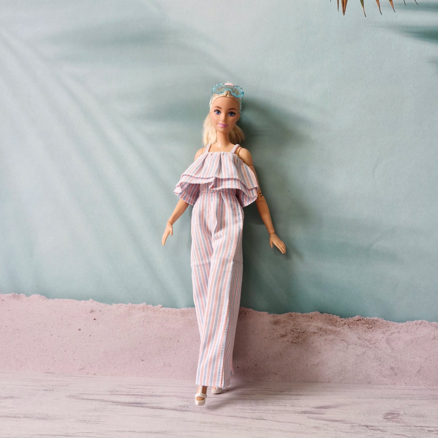 Barbie doll walking in stylish striped wide-leg jumpsuit with off-shoulder ruffle.