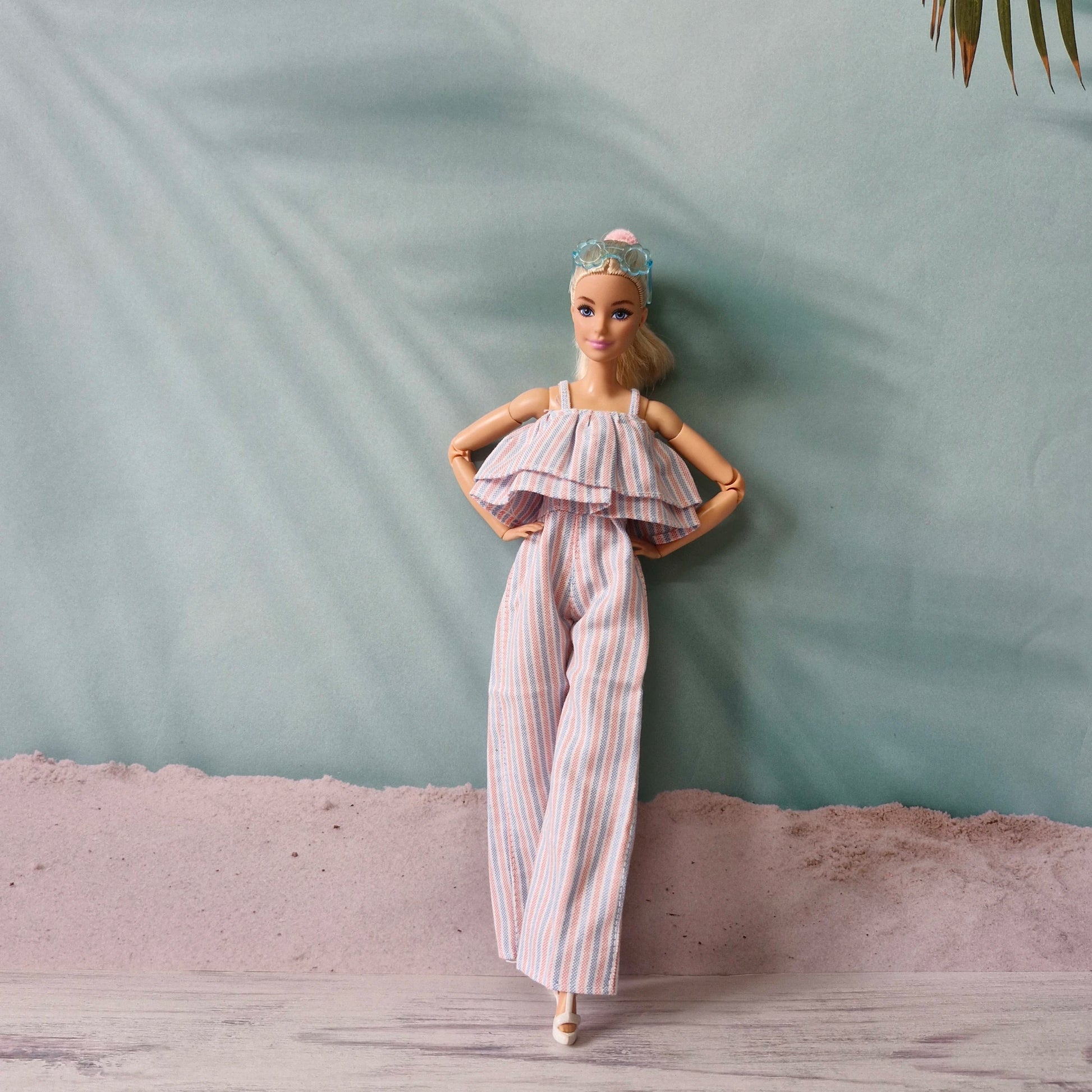 Barbie doll posing confidently in pastel striped ruffle jumpsuit, hands on hips.