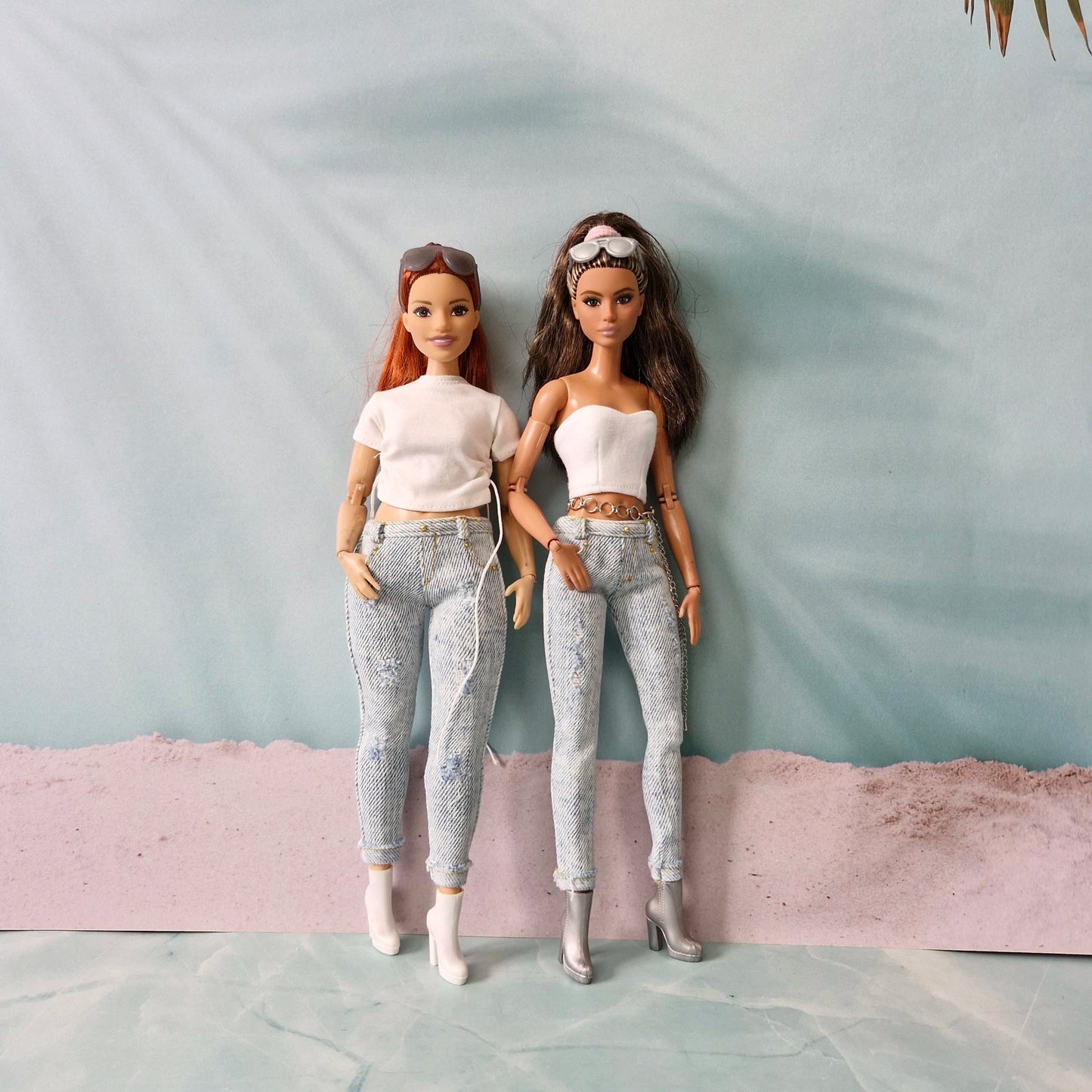 Two Barbie dolls, a curvy redhead and a brunette, side-by-side wearing matching light-wash distressed jeans and white tops.