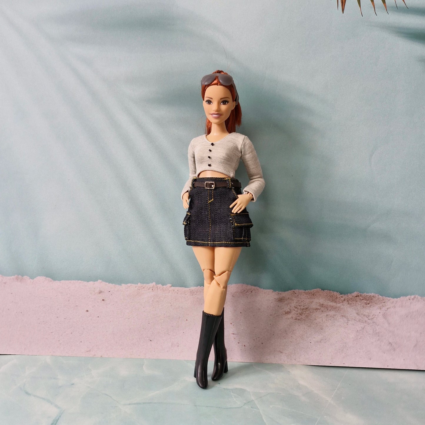 Barbie doll wearing a beige top and denim skirt on a plain background