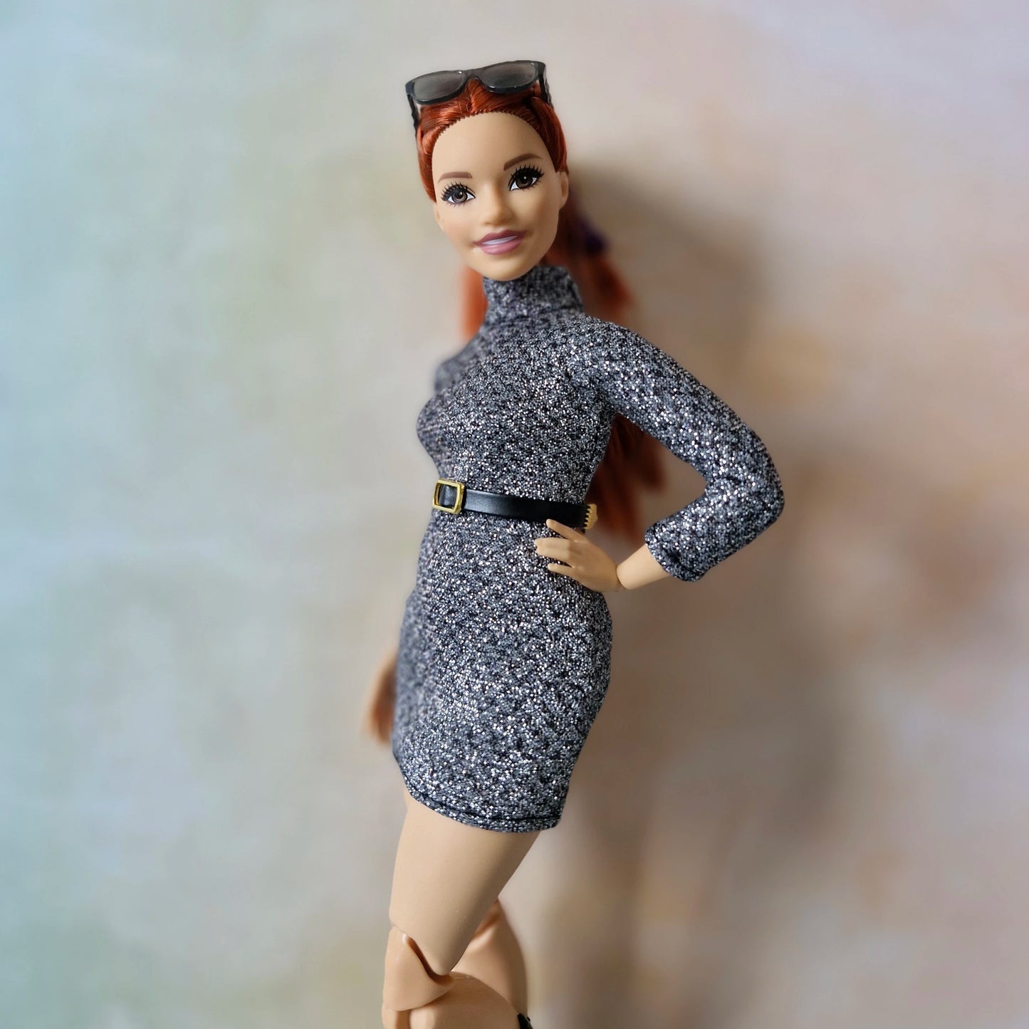 Barbie doll wearing a patterned dress with a belt against a plain background