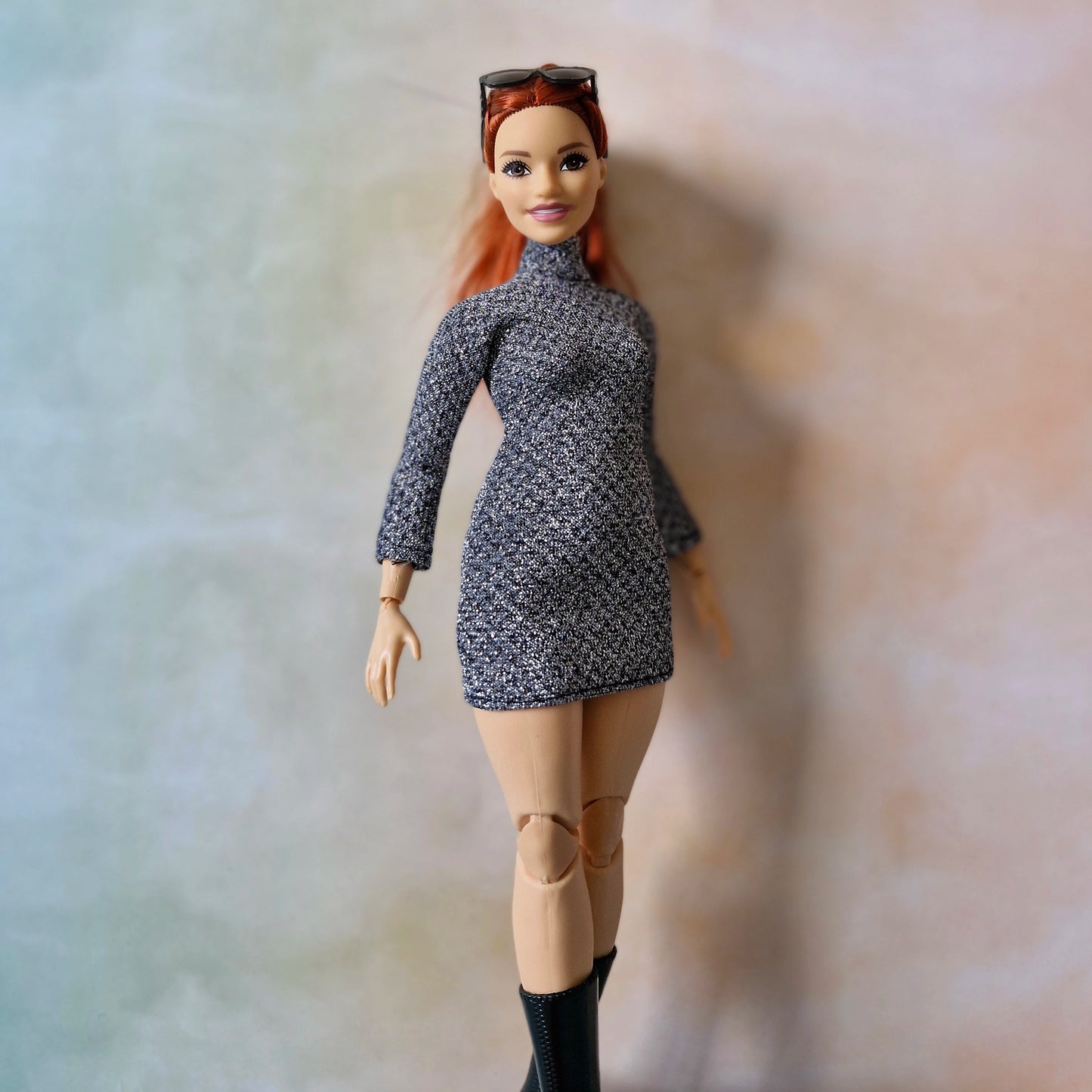 Barbie doll with red hair wearing a patterned dress against a neutral background