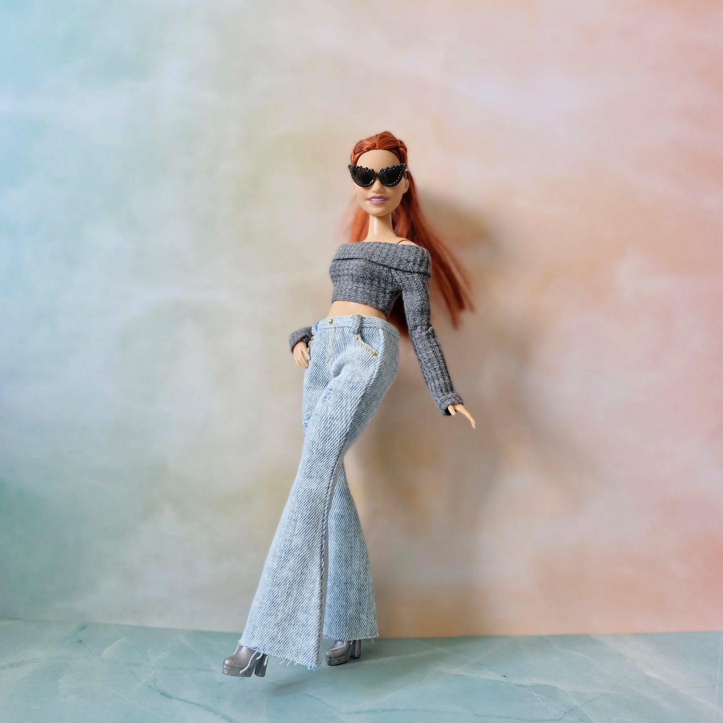 Barbie curvy doll posing in gray top, flared jeans, and black sunglasses