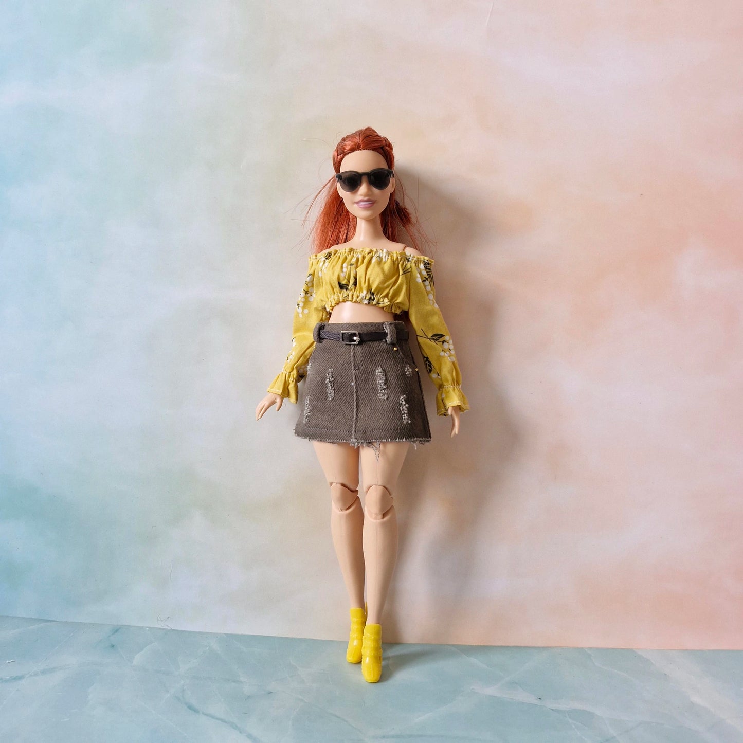 Doll wearing a yellow top and denim skirt against a gradient background