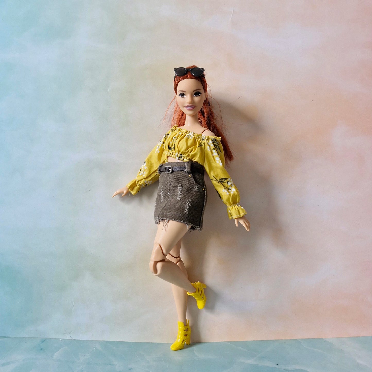 Barbie doll in yellow top and denim skirt on a neutral background