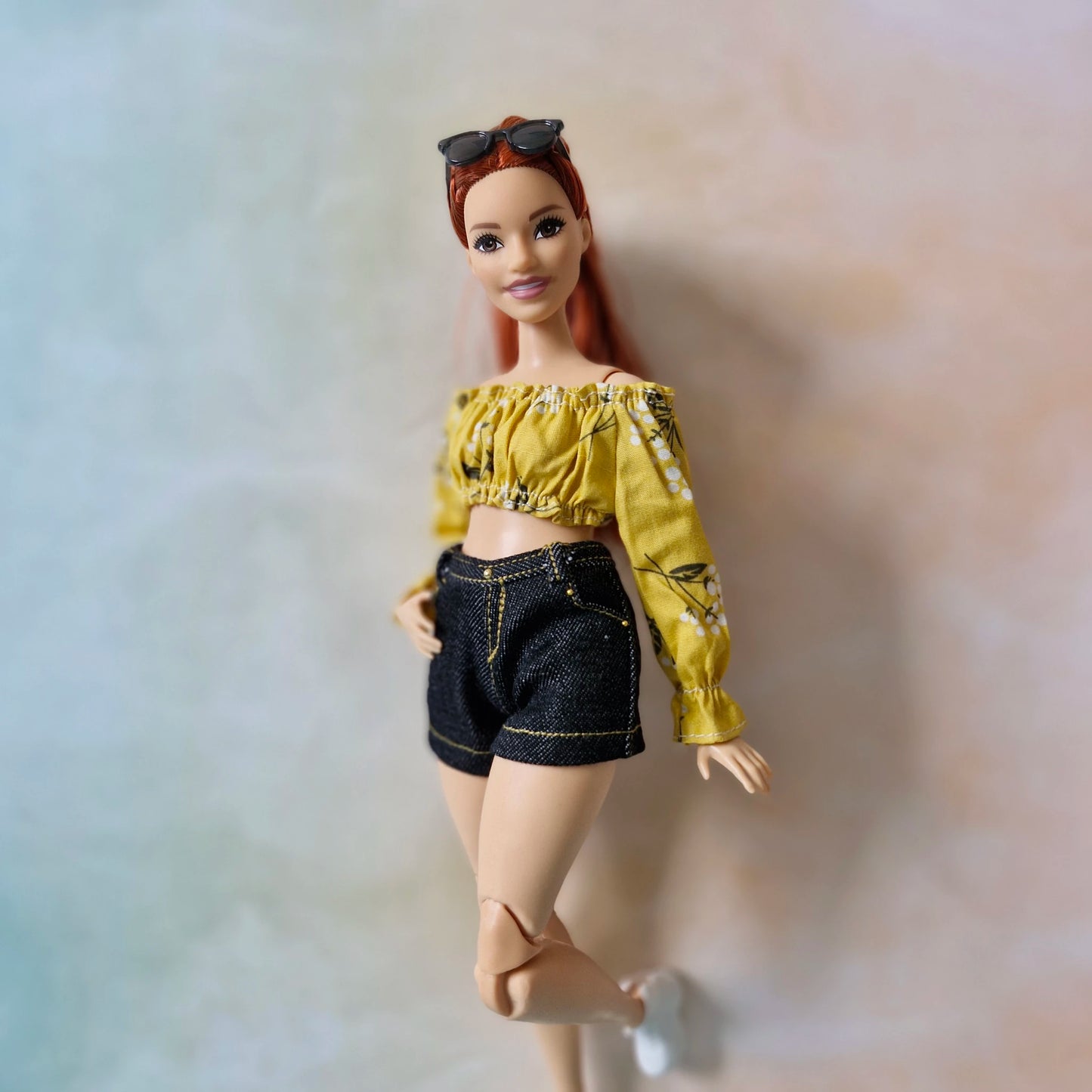 Side view of Curvy Barbie modeling a yellow crop top and black denim shorts.