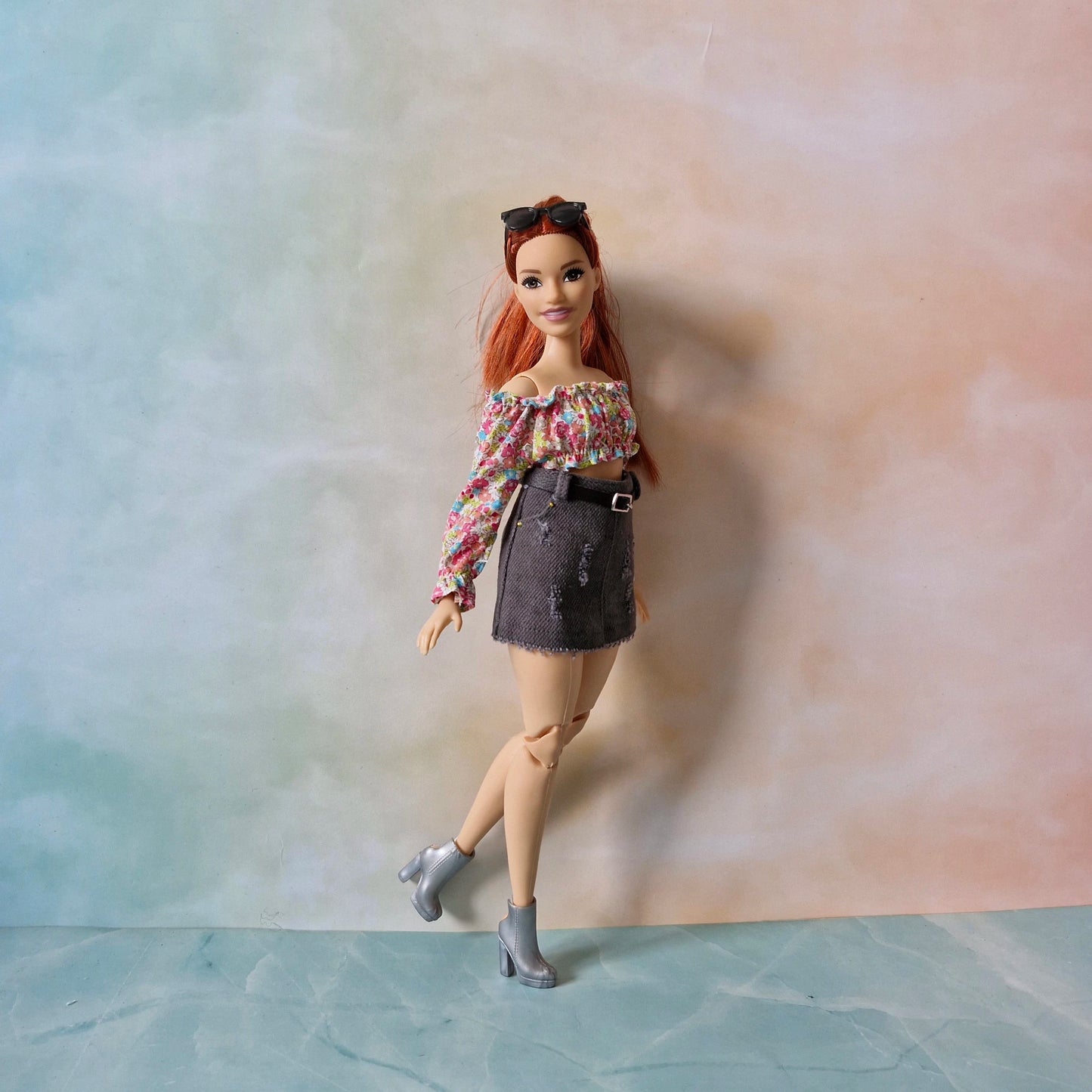 Full view of Curvy Barbie modeling the floral top, grey skirt, and silver boots outfit.