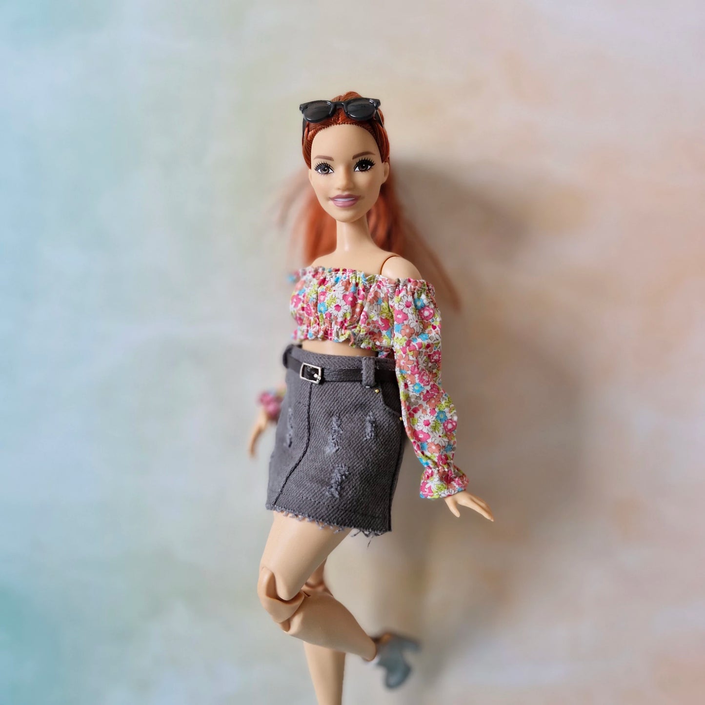 Barbie doll with floral top and denim skirt on a blurred background