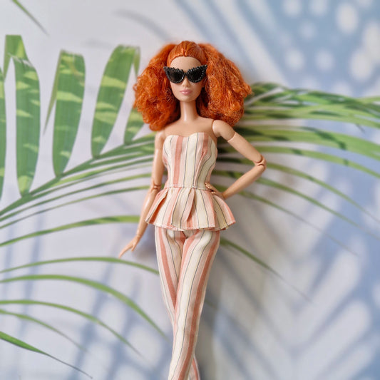 Barbie doll in a striped outfit with sunglasses against a leafy background