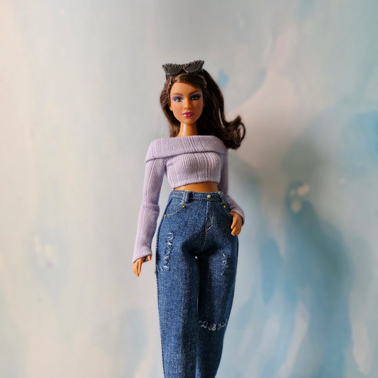 Barbie doll wearing a purple top and blue jeans with a blurred background