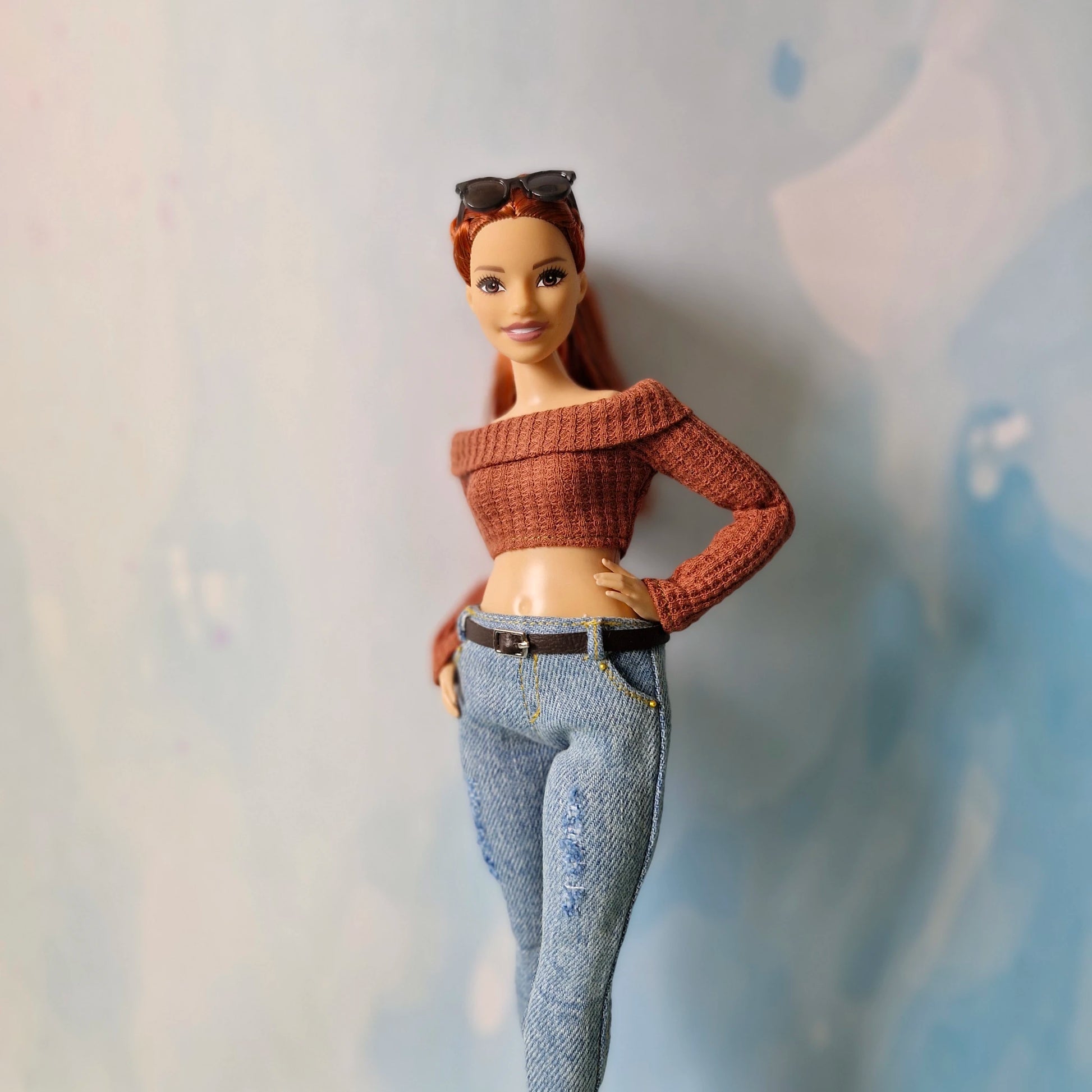 Barbie doll wearing a brown sweater and blue jeans against a light background