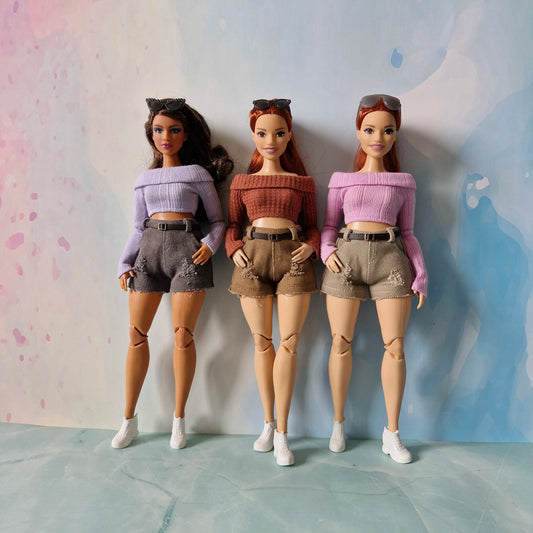 Three dolls in matching outfits standing against a colorful background