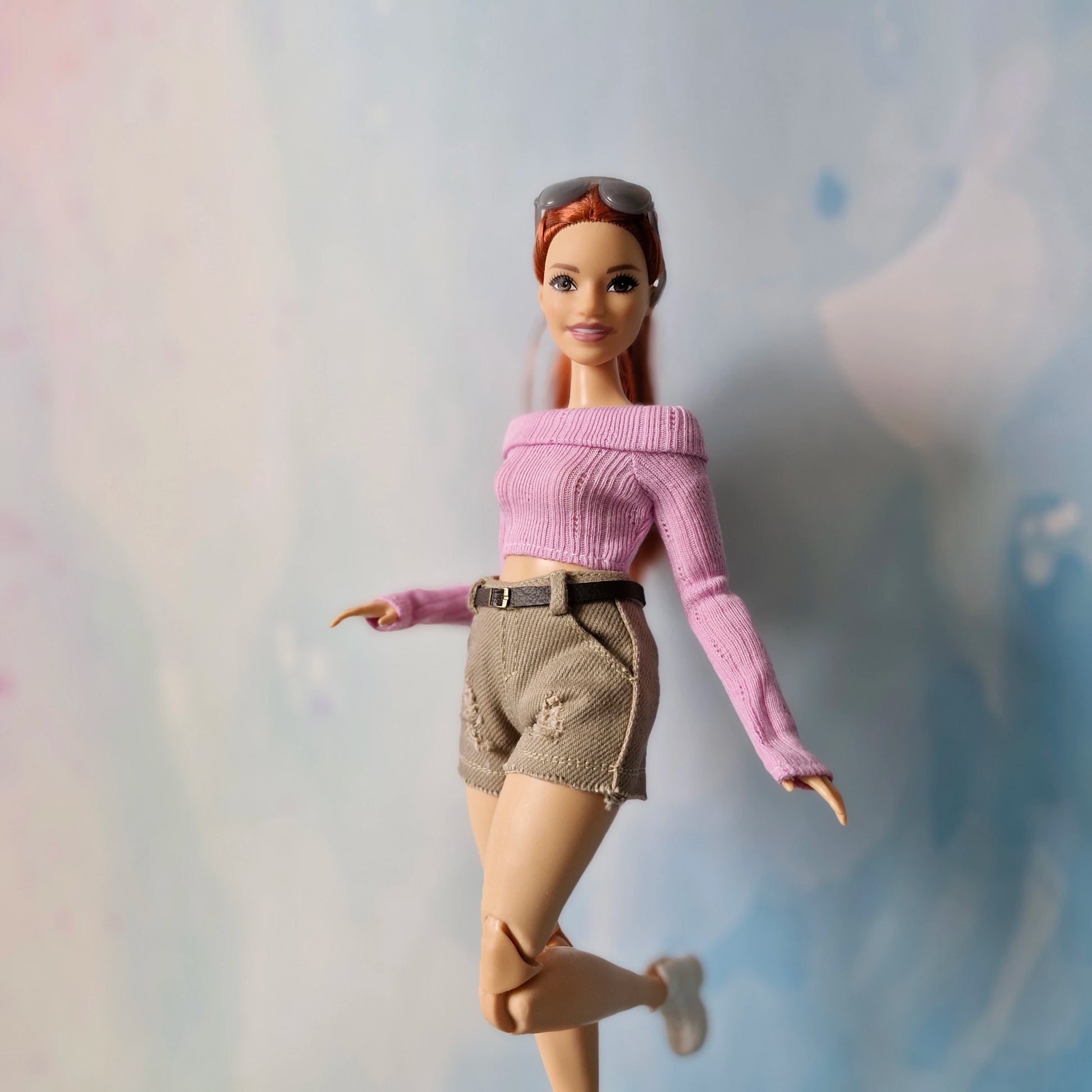 Barbie doll wearing a pink sweater and beige shorts on a light background