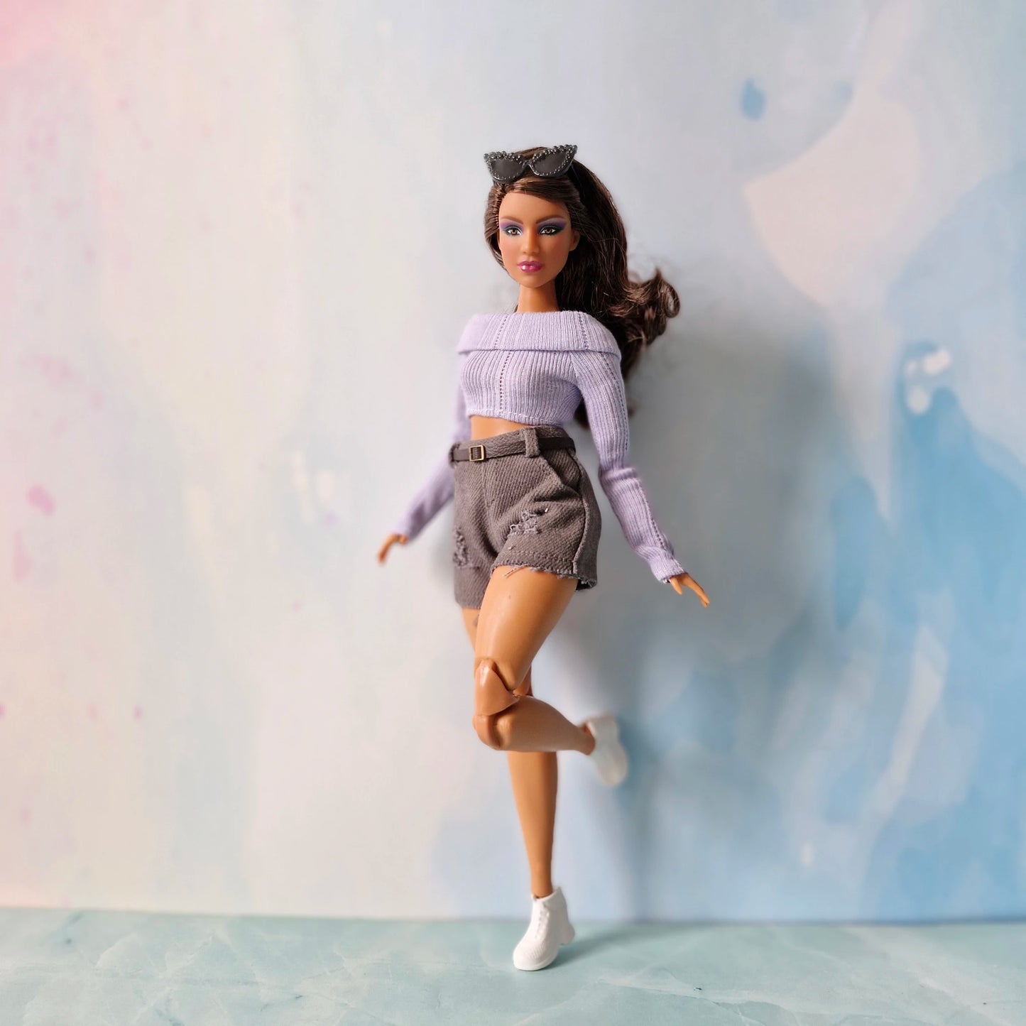 Barbie doll in a purple top and shorts with a blurred background