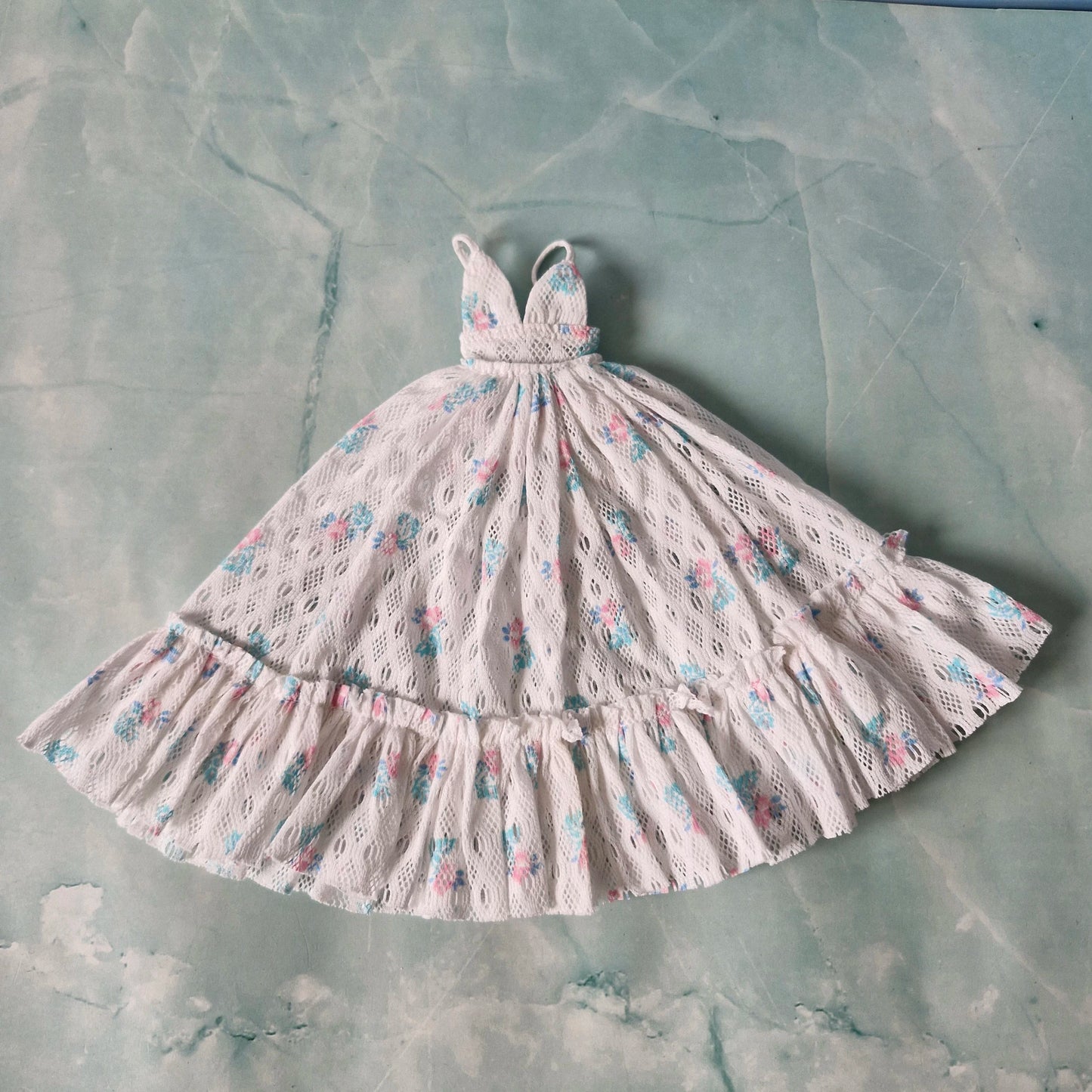 Flat lay of white lace Barbie maxi dress with floral patterns