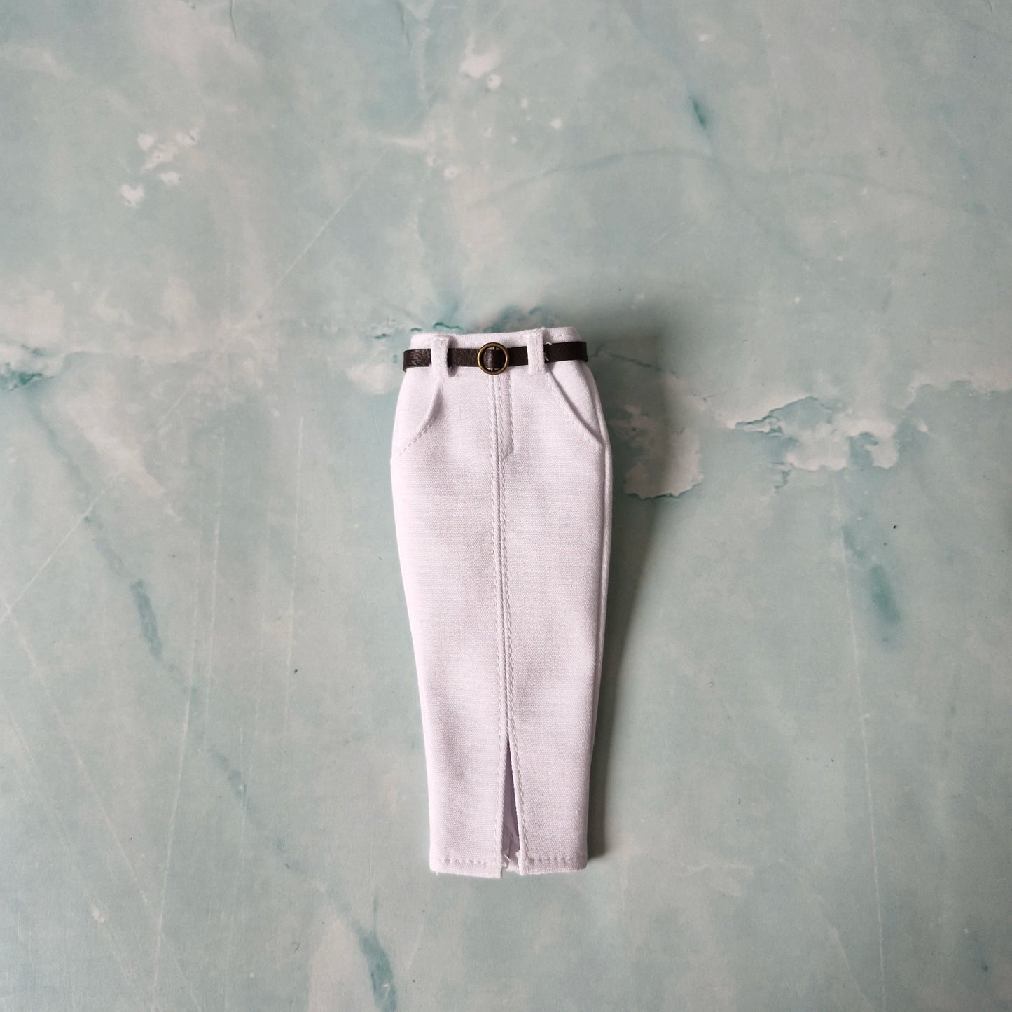 White pants with a black belt on a textured gray background